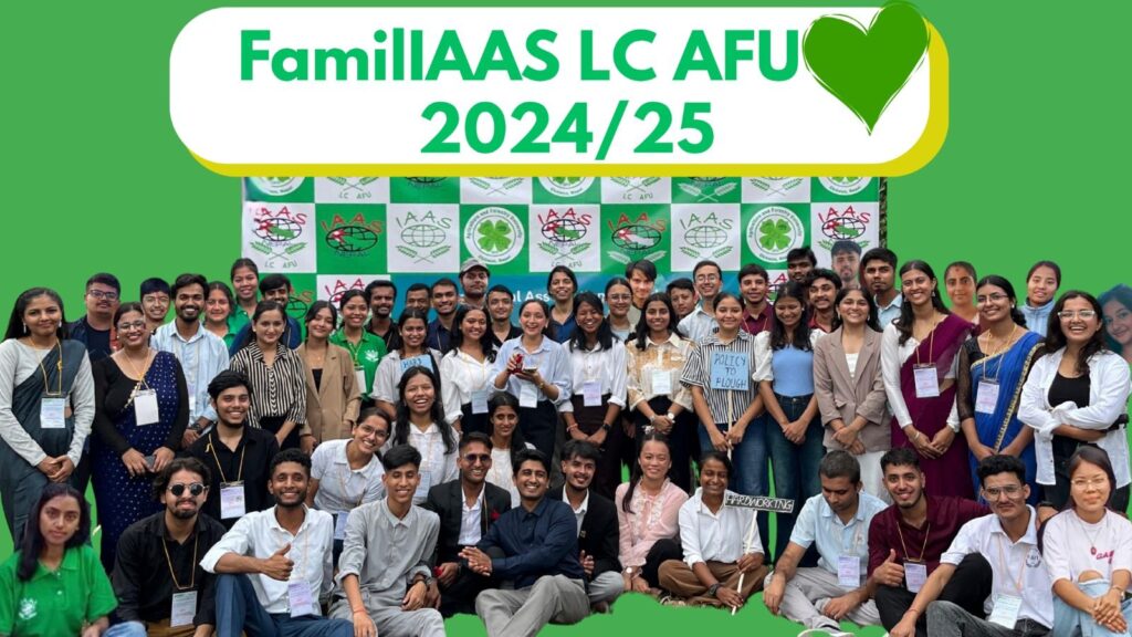 Large group photo of the FamillAAS LC AFU 2024/25 team, with members standing and sitting in front of a green IAAS banner. A green heart logo is at the top right.